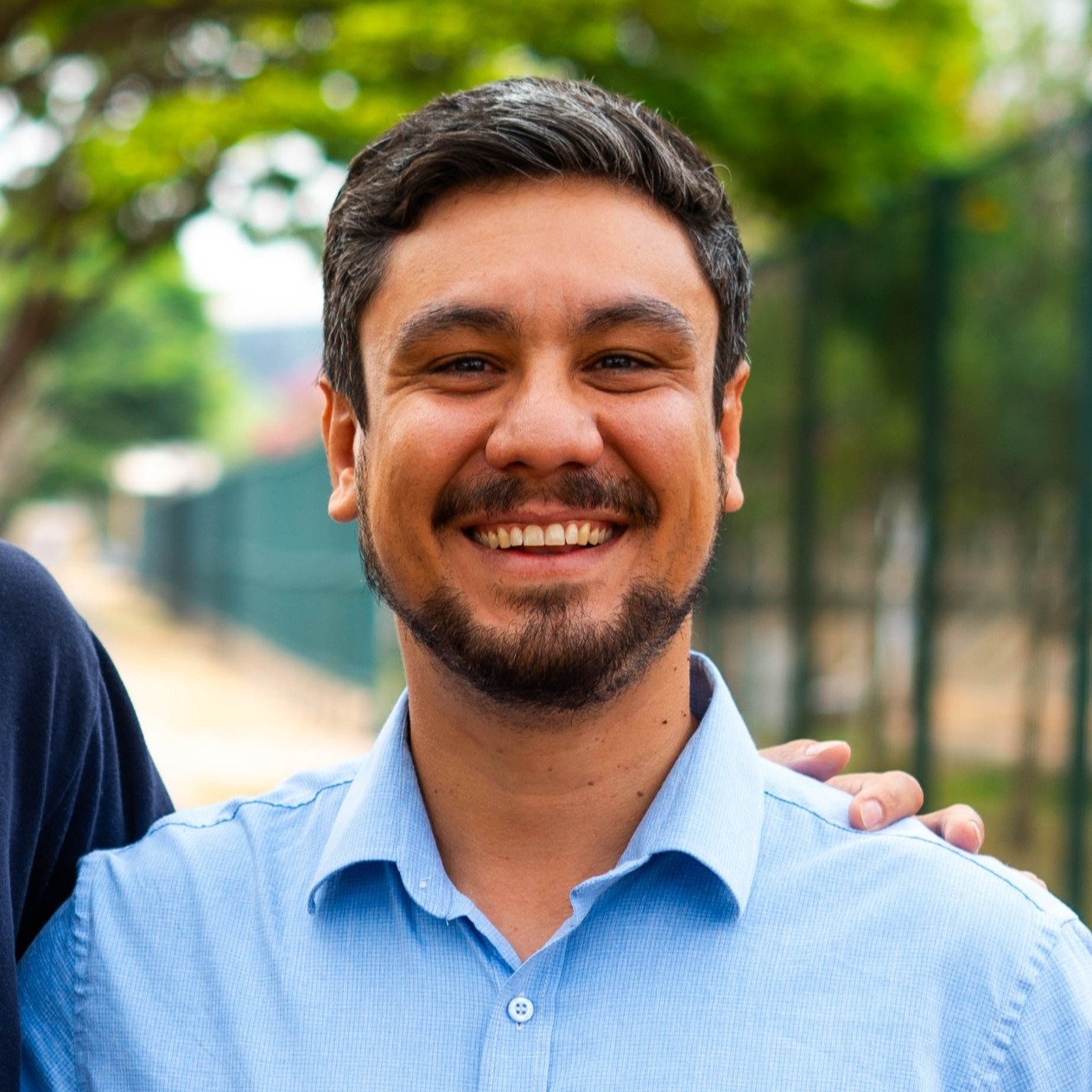 Foto de Lucas Pimenta, com cabelos curtos e escuros, sorrindo e olhando diretamente para a câmera.